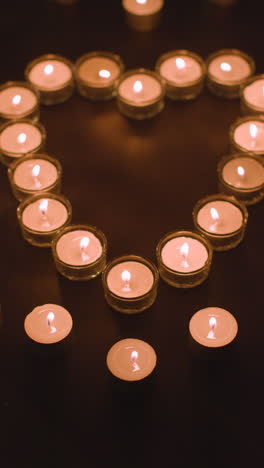 Vertical-Video-Of-Romantic-White-Candles-In-the-Shape-Of-A-Heart-On-Black-Background